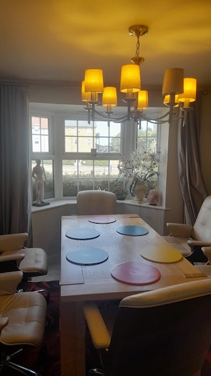A dining area with a table set for four, surrounded by chairs, and a window with a view of greenery.