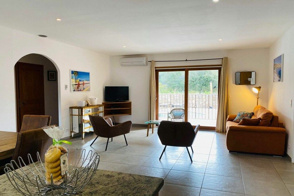 Ein modernes Wohnzimmer mit einem Flachbildfernseher, zwei Sesseln, einer Couch und einem Essbereich mit einem Marmortisch.