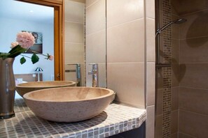 Ein Badezimmer mit zwei großen Steinsinks, einer Dusche und einer gefliesten Rückwand.