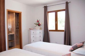 Ein Schlafzimmer mit einem Bett, einem Schminktisch, einem Fenster mit Vorhängen und einer Duschkabine.