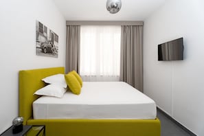 A hotel room with a bed, a flat-screen TV, a painting on the wall, and a window with curtains. - Domus Rubina - terrace sea view (Sorrento)
