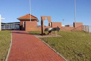 A paved pathway leading to a building with a red-tiled roof. - Holiday home with 2 bedrooms (Butjadingen)