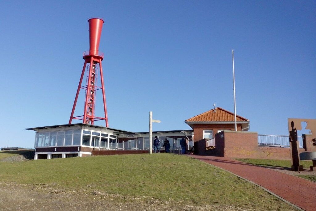 Ein Gebäude mit einem hohen, roten Turm, einem überdachten Gang und einem kleinen Anbau.