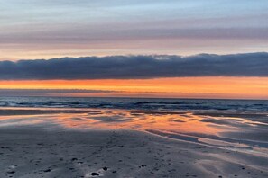 A beach with a sunset, calm water, and footprints in the sand. - Holiday home with 1 bedroom (Blonville-sur-Mer)
