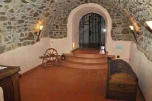 Ein Zimmer mit Steinwänden, einer hölzernen Bank, einem Spinnrad und einer Treppe, die zu einer Tür führt.