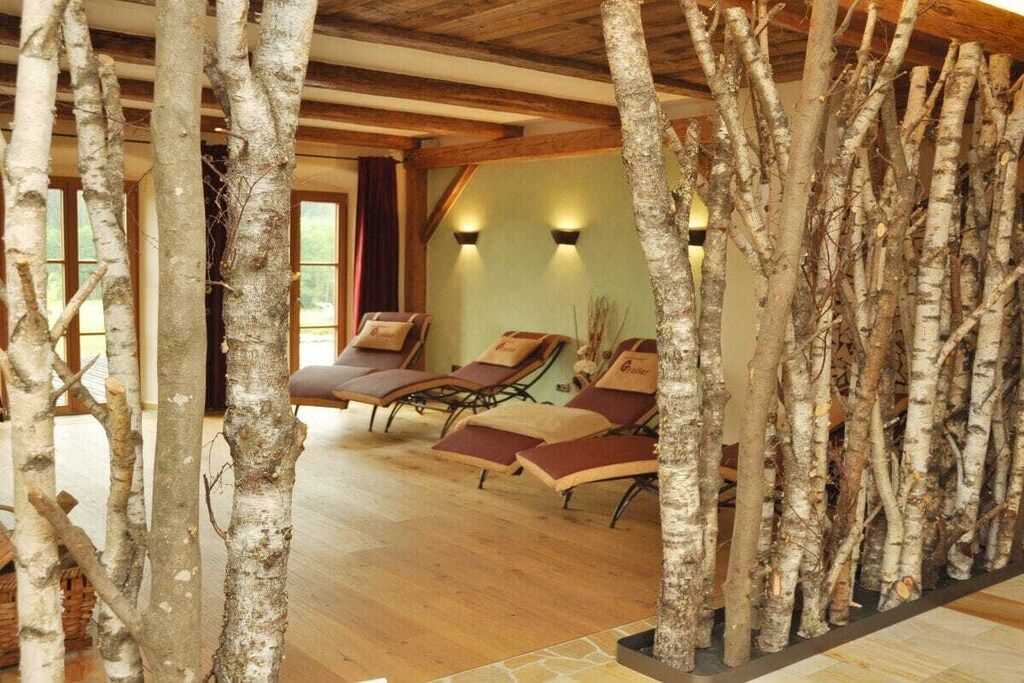 Une pièce dont un des murs est constitué de branches de bouleau, avec un plancher en bois et deux fauteuils inclinables dotés de coussins.