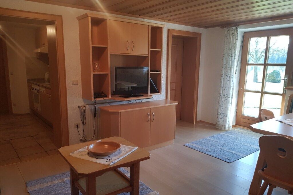 Una cocina con armarios de madera, un televisor y un comedor con mesa y sillas.