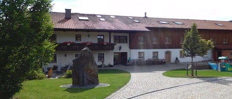 Un edificio con techo de tejas, un sendero de piedra y un área verde.