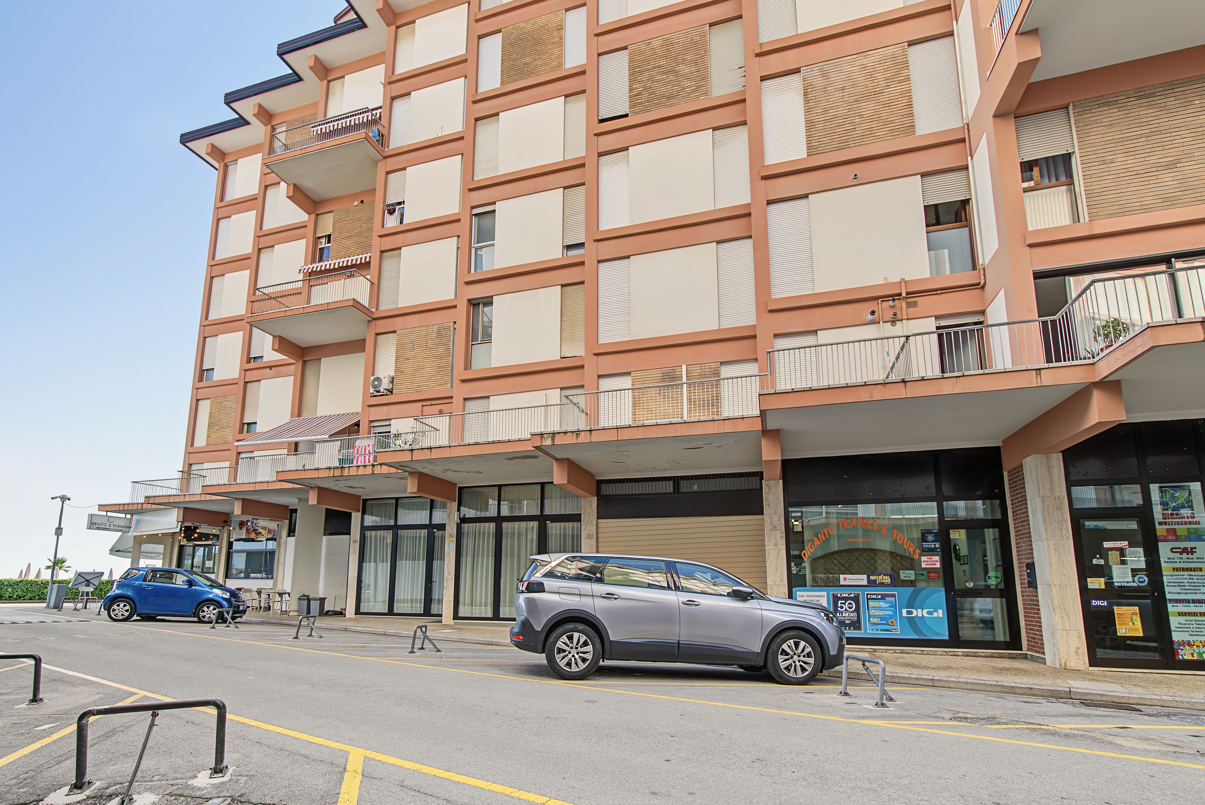 Un hotel a più piani con balconi, un parcheggio e un negozio con insegne.