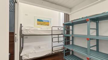 A bunk bed room with a painting on the wall and a blue metal shelf unit.