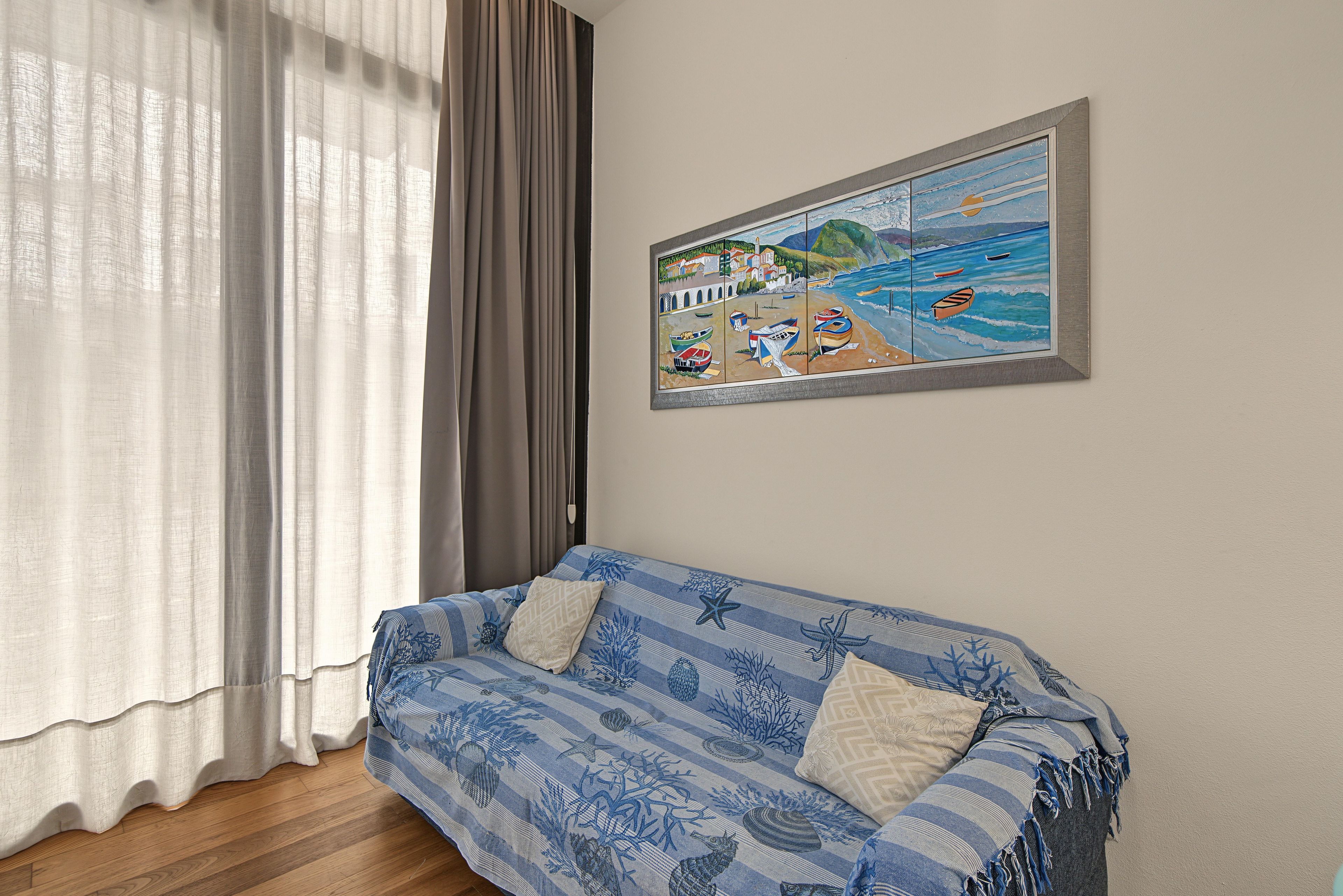 Une pièce avec un canapé, un tableau et une fenêtre avec des rideaux.