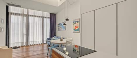 A modern kitchen with a central island, a dining area with a round table, and a living space with a sofa and curtains.