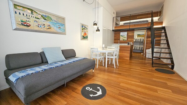 Un espacio habitable moderno con sofá, mesa de comedor y una escalera que conduce a un nivel superior.