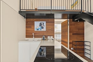 Una cucina moderna con un piano di lavoro nero, rivestimenti in legno a parete e un'opera d'arte appesa.