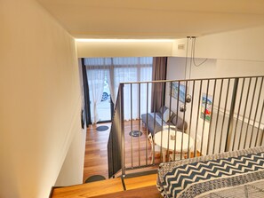 Un interior moderno con una escalera que lleva a una sala de estar, una mesa de comedor y un sofá.