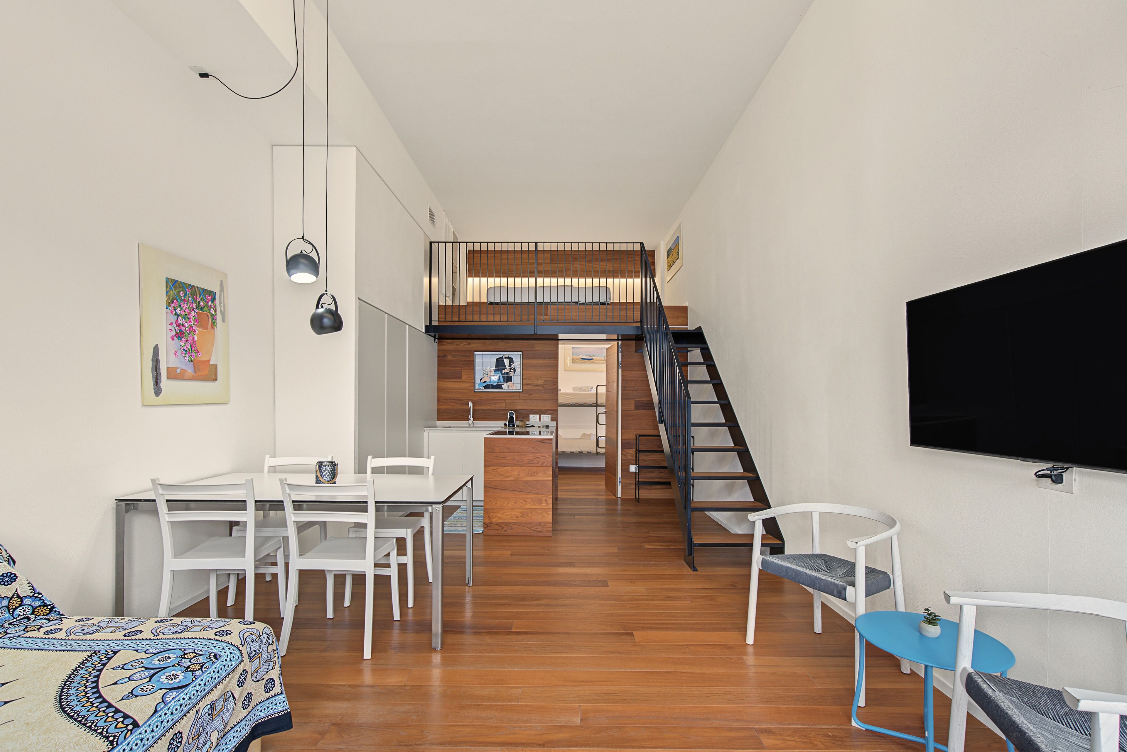 Un intérieur moderne comprenant un espace repas, une cuisine et un escalier menant à un niveau supérieur.
