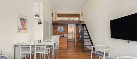 A modern interior with a dining area, kitchen, and a staircase leading to an upper level.