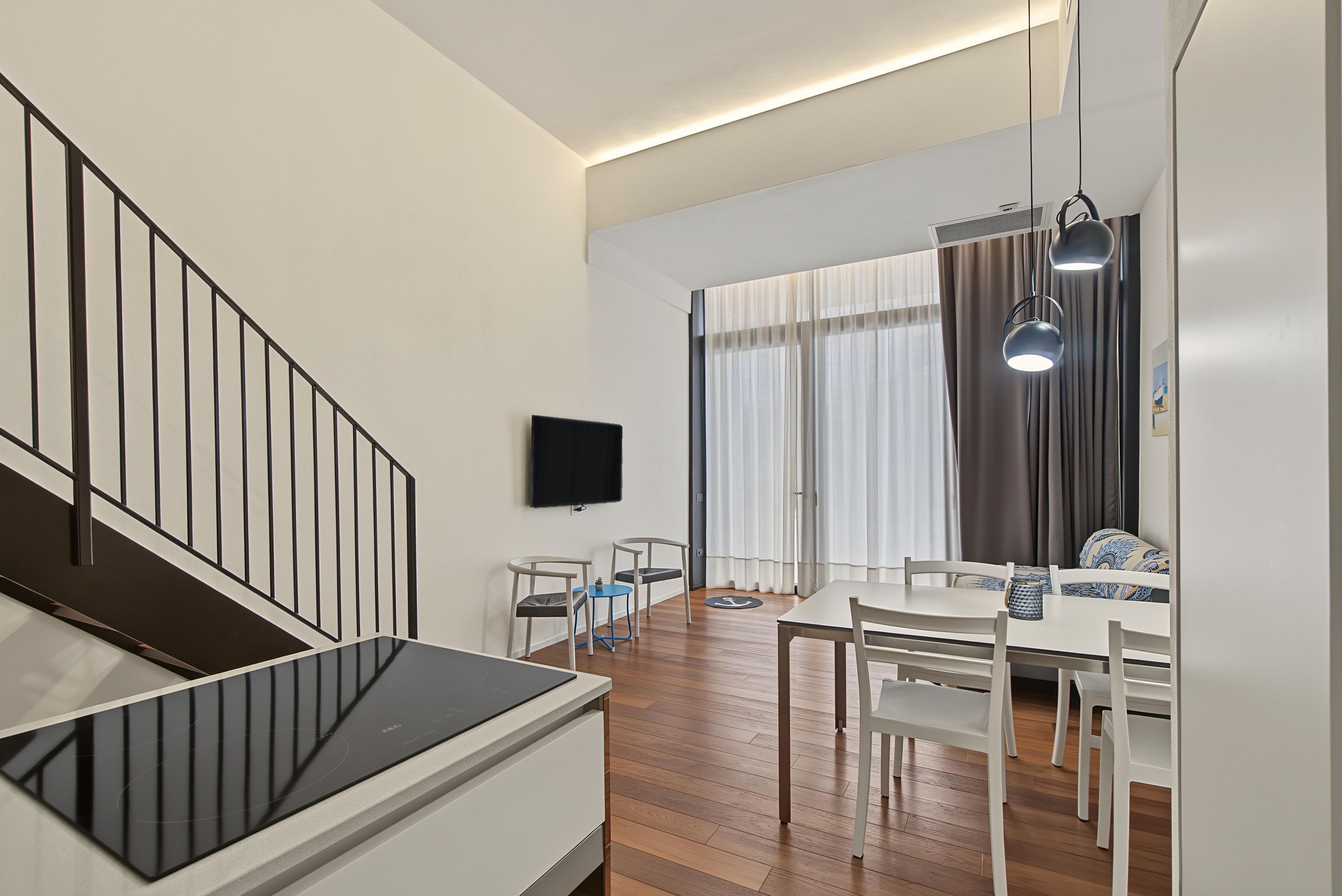 Ein moderner Wohnraum mit Treppe, Essbereich und einem an der Wand befestigten Flachbildfernseher.