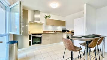 Een moderne keuken met een eethoek, roestvrijstalen apparatuur en een groot raam.
