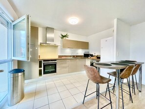A modern kitchen with a dining area, stainless steel appliances, and a large window. - L'atelier Chic - Balcony, Netflix, Parking, 2-room apartment (Lanester)