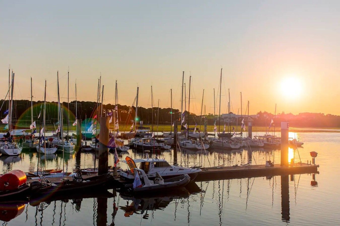 Un puerto deportivo con varias embarcaciones amarradas al muelle al atardecer.