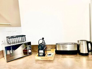 A kitchen with a toaster, a coffee maker, and a kettle.