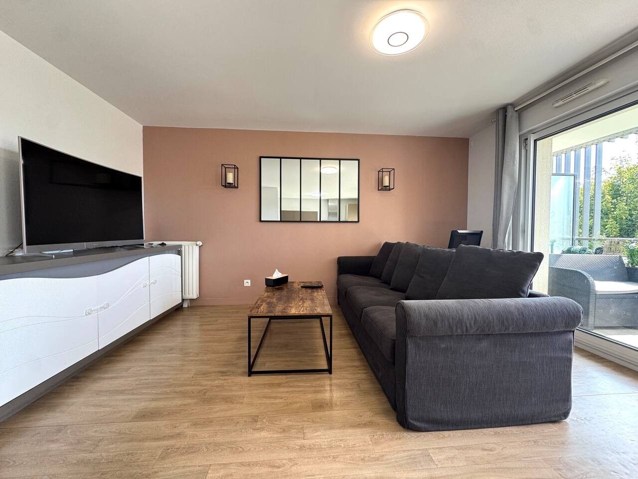Ein modernes Wohnzimmer mit einer Couch, einem Couchtisch und einem Fernseher auf einem Schrank.