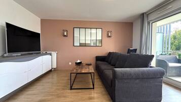Ein modernes Wohnzimmer mit einer Couch, einem Couchtisch und einem Fernseher auf einem Schrank.