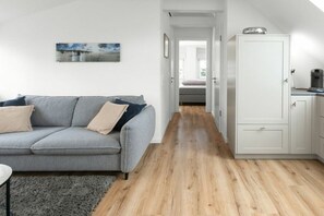 A modern living room with a grey sofa, a coffee machine, and a cabinet. - 272 - Apartment Lighthouse (Juist)