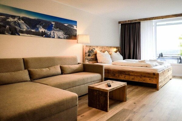 Una habitación de hotel con cama, sofá, una mesita y un cuadro en la pared.