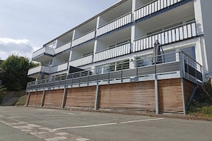 A multi-story building with balconies, a covered entrance, and a parking area. - Holiday apartment 603 (Winterberg)