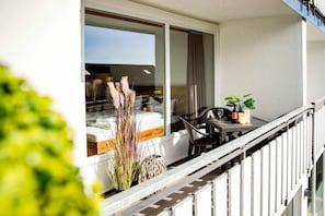 Un balcon avec une table, des chaises et un pot de fleurs.