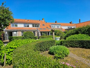 A residential building with a garden in front, featuring a pathway and various plants. - Studio Zoet Do46 Domburg (Domburg)