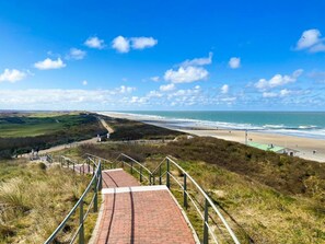 A coastal pathway leading to a beach with a clear view of the ocean and distant hills. - Studio Zoet Do46 Domburg (Domburg)