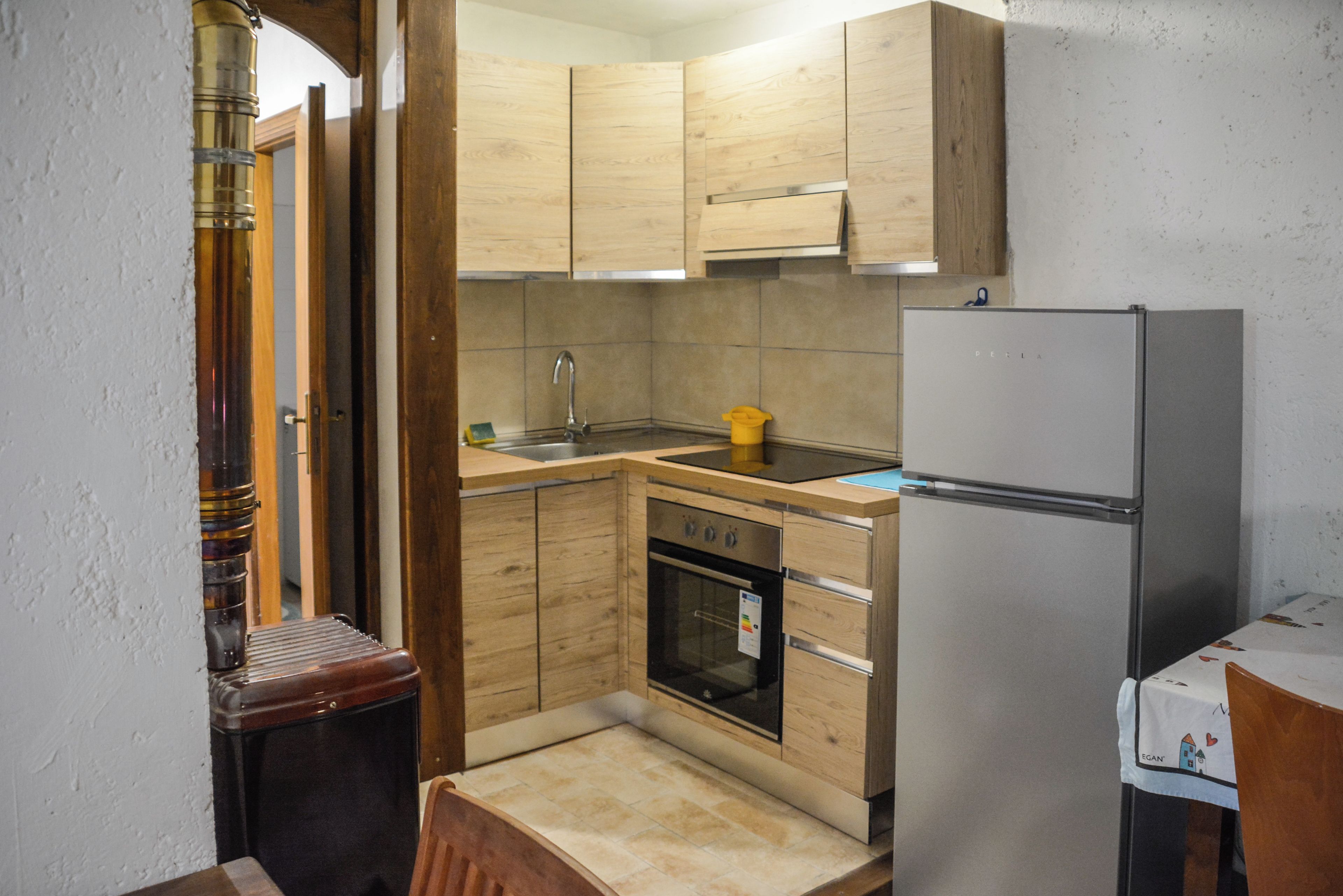 Een compacte keuken met houten kastjes, een roestvrijstalen spoelbak en een ingebouwde oven.