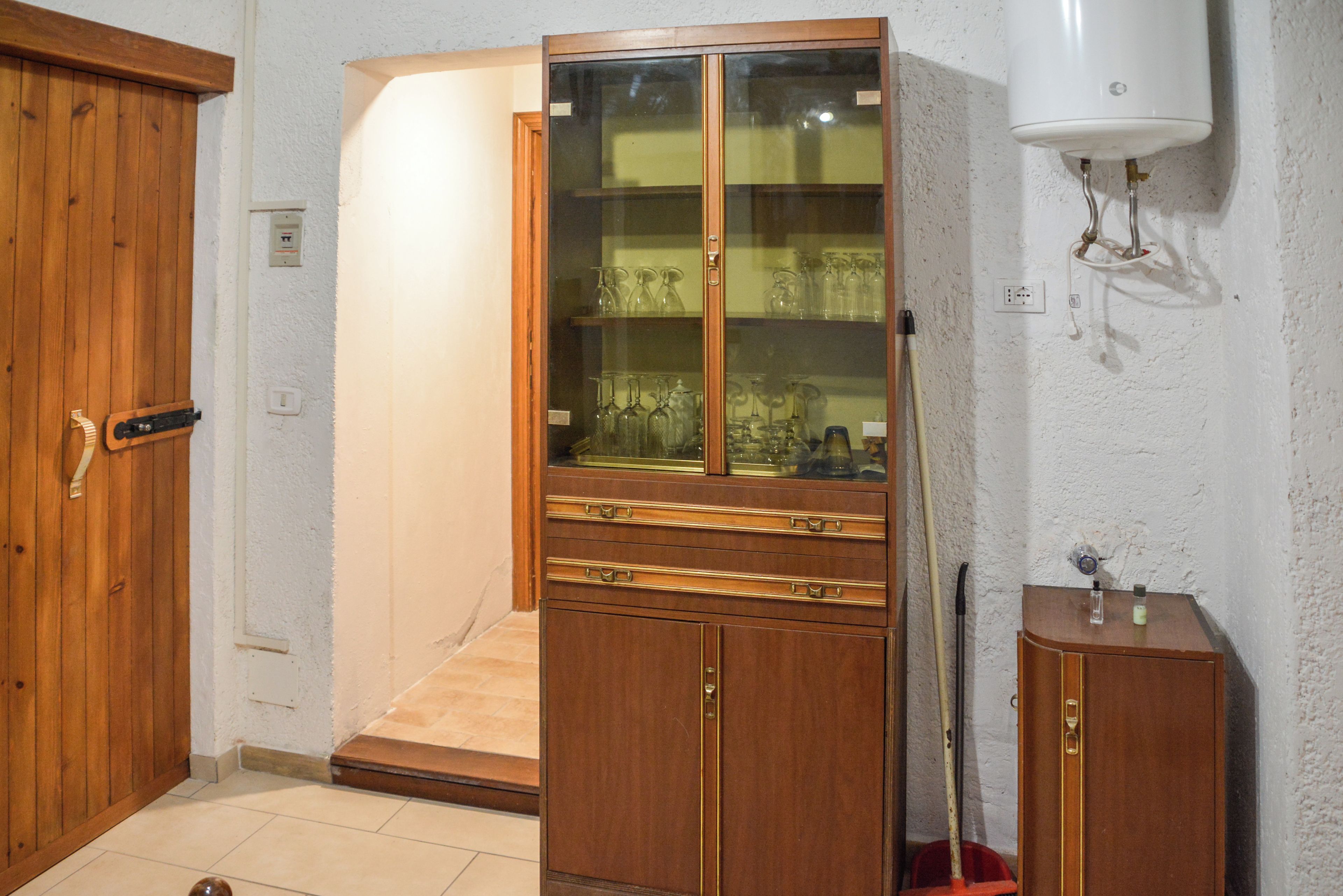 Ein Zimmer mit einem Holzkabinett, einer Glasvitrine und einem Mopp.