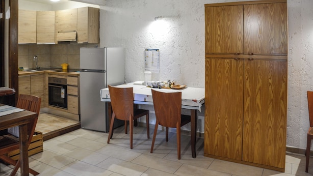 A compact kitchen with wooden cabinets, a refrigerator, and a dining table with chairs. - Tavernetta Openspace (Sparvo)