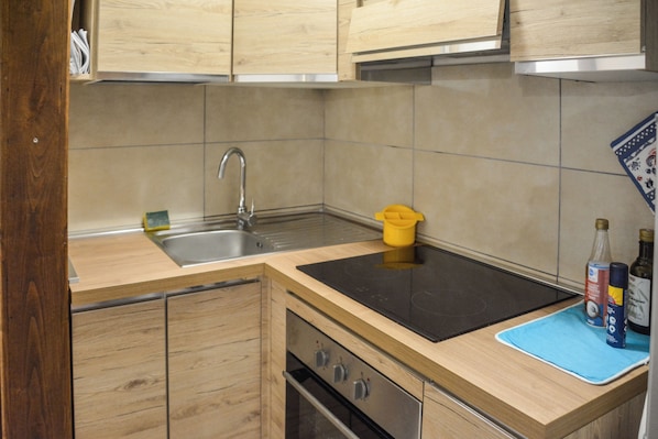 A kitchen with wooden cabinets, a stainless steel sink, a black countertop, and a blue mat. - Tavernetta Openspace (Sparvo)