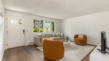 A modern living room with a sofa, two armchairs, a coffee table, and a television.