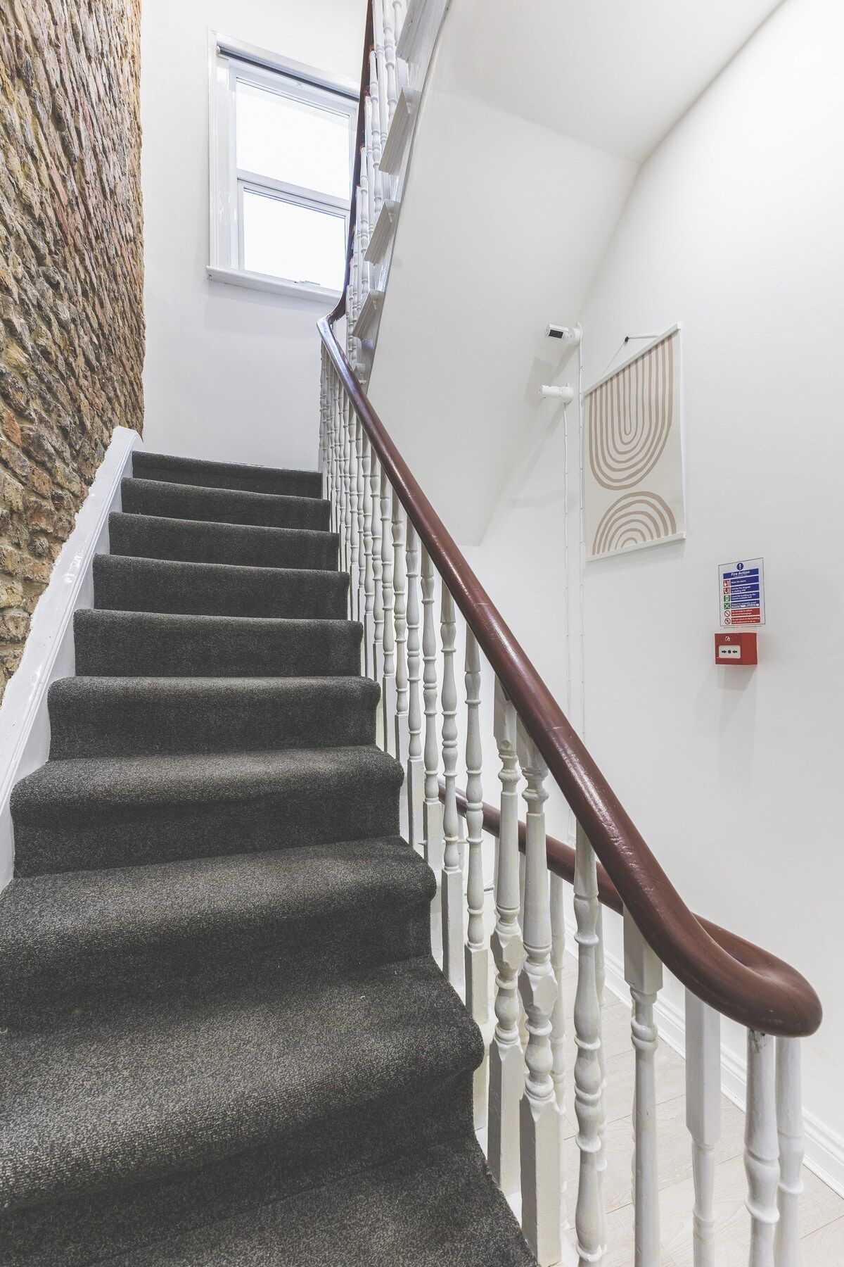 A staircase with dark carpeted steps, white balusters, and a brown handrail.