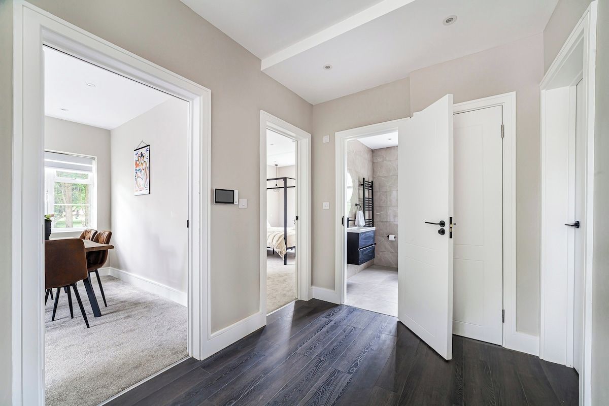Een gang met een donker houten vloer, witte wanden en een deur naar een badkamer.