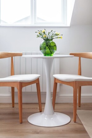 A table with a vase of flowers, two chairs, and a window in the background. - Contemporary Studio with Parking, Finsbury Park (Greater London)