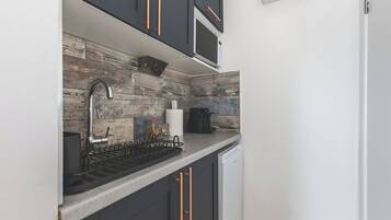 A modern kitchen with dark cabinetry, a stainless steel sink, and a built-in microwave.