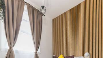 A modern bedroom with a bed, wooden panel wall, and a herringbone floor pattern.