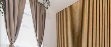 A modern bedroom with a bed, wooden panel wall, and a herringbone floor pattern.