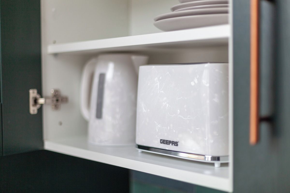 A white cabinet with a coffee maker and a white appliance with the brand 'DEEPAS' on it.