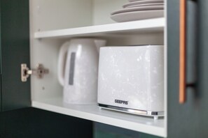 Ein weißes Schranksystem mit einer Kaffeemaschine und einem weißen Gerät der Marke 'DEEPAS'.