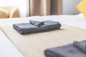 A neatly made bed with a folded gray blanket and a beige textured bedspread. - Lovely Studio Flat in Kilburn w/great location (Greater London)