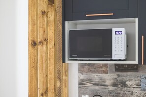 A microwave oven with a digital display in a kitchen cabinet. - Large Studio Flat - Highbury Great Location (Greater London)