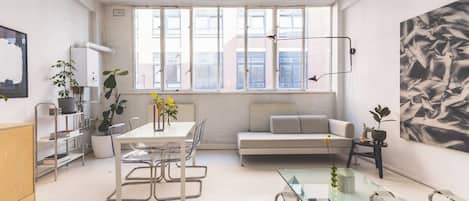 A modern interior with a dining area, sofa, and artwork.